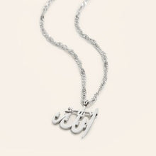 A bold silver necklace featuring Allah’s name in Arabic calligraphy, worn at a 16-inch length.

