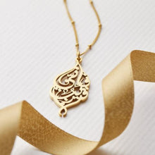 A silver dotted chain necklace featuring Arabic calligraphy of the Qur’anic verse 