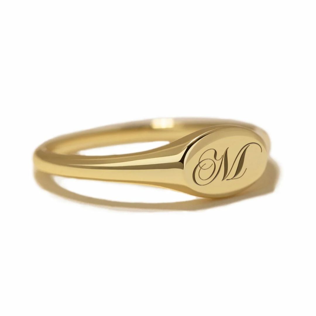 A classic personalized oval signet ring in 18k gold-plated sterling silver, engraved with a 'J' monogram and worn on a finger.