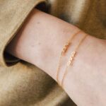 Whisper-thin 'Zoe' name bracelet in 18k gold-plated sterling silver, shown delicately on a woman's wrist.
