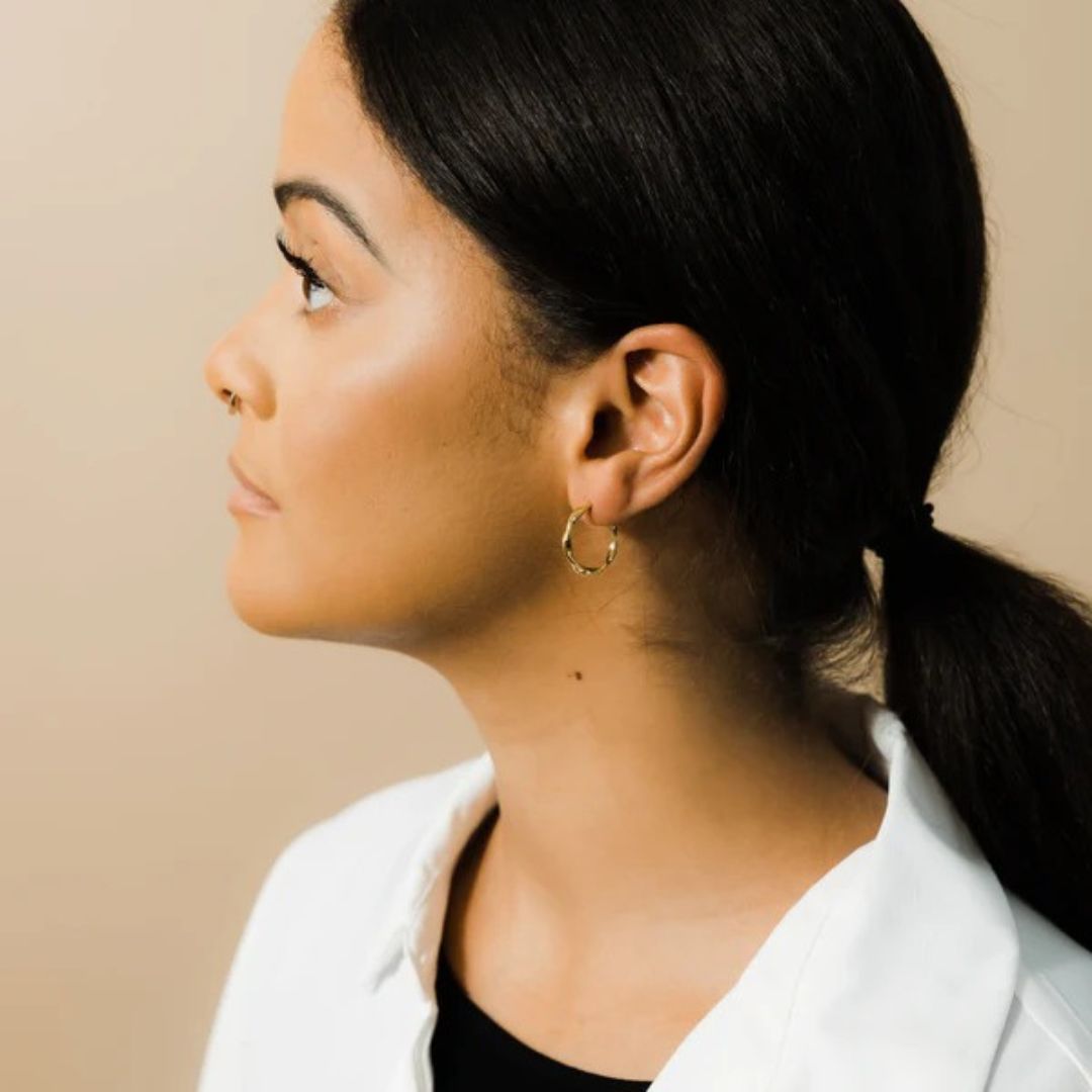 A pair of Liquid Ripple Hoop Earrings in 18k gold-plated sterling silver, showcasing their unique textured, light-catching surface.