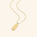 "With Hardship Comes Ease" verse bar necklace in 18k gold-plated sterling silver, showing the vertical pendant with Arabic calligraphy.