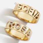 A personalized 14k solid gold ring, engraved with the name 'Elizabeth', shown on a woman's finger.