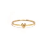 A dainty personalized heart initial 'A' ring in 18k gold-plated sterling silver, worn on a woman's finger.