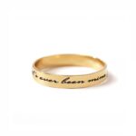 A personalized message ring in 18k gold-plated sterling silver, worn on a finger and engraved with the words 'Je t'aime'.