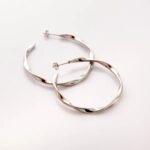 A pair of Liquid Ripple Hoop Earrings in 18k gold-plated sterling silver, showcasing their unique textured, light-catching surface.