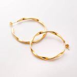 A pair of Liquid Ripple Hoop Earrings in 18k gold-plated sterling silver, showcasing their unique textured, light-catching surface.