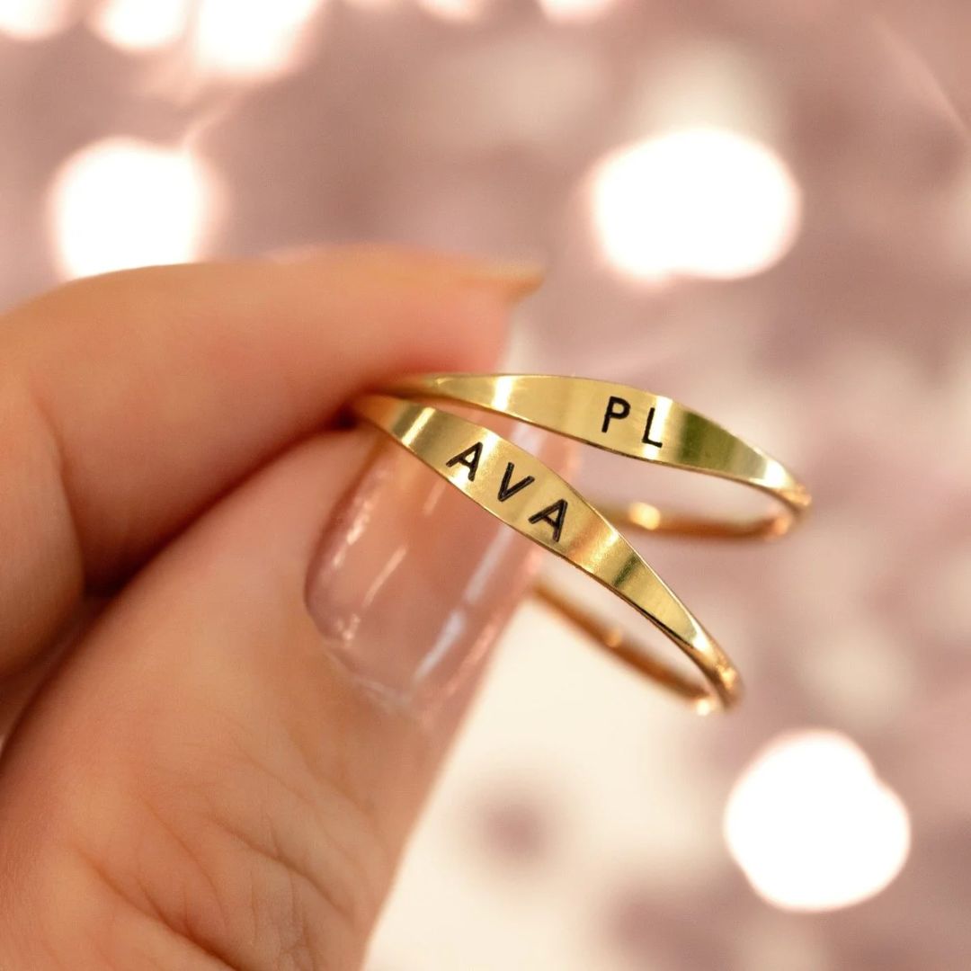 A dainty personalized signet ring in 18k gold-plated sterling silver, engraved with the initial 'S' and worn on a finger.