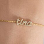 Dainty 'Madison' name bracelet in 18k gold-plated sterling silver, fully 'iced out' with sparkling crystals, on a woman's wrist.