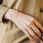 Whisper-thin 'Zoe' name bracelet in 18k gold-plated sterling silver, shown delicately on a woman's wrist.