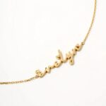 A delicate romantic script heart bracelet in 18k gold-plated sterling silver, worn on a woman's wrist.
