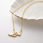 Personalized 'Amanda' name necklace in 18k gold-plated sterling silver, hanging from a delicate chain on a neutral background.
