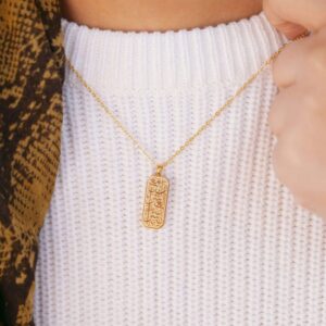 "With Hardship Comes Ease" verse bar necklace in 18k gold-plated sterling silver, showing the vertical pendant with Arabic calligraphy.