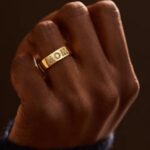 A personalized 14k solid gold ring, engraved with the name 'Elizabeth', shown on a woman's finger.