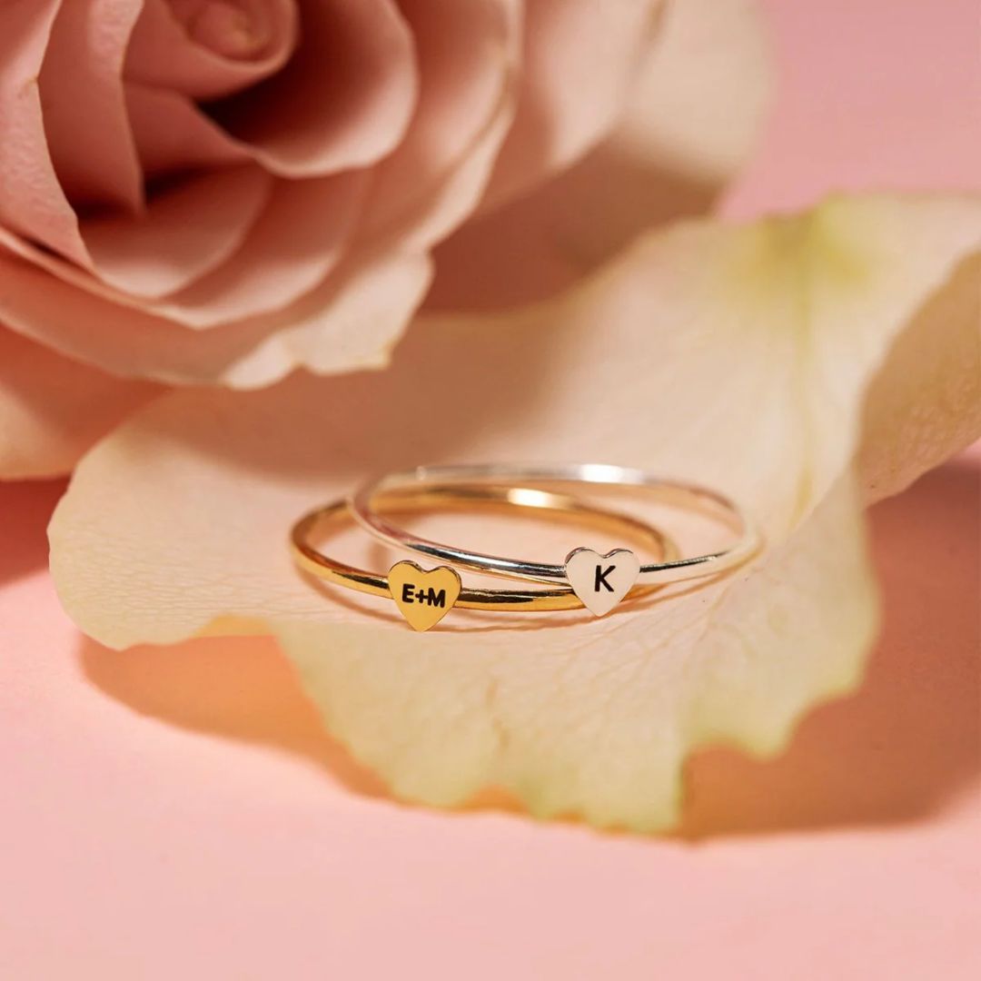 A dainty personalized heart initial 'A' ring in 18k gold-plated sterling silver, worn on a woman's finger.