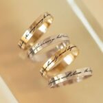 A personalized message ring in 18k gold-plated sterling silver, worn on a finger and engraved with the words 'Je t'aime'.