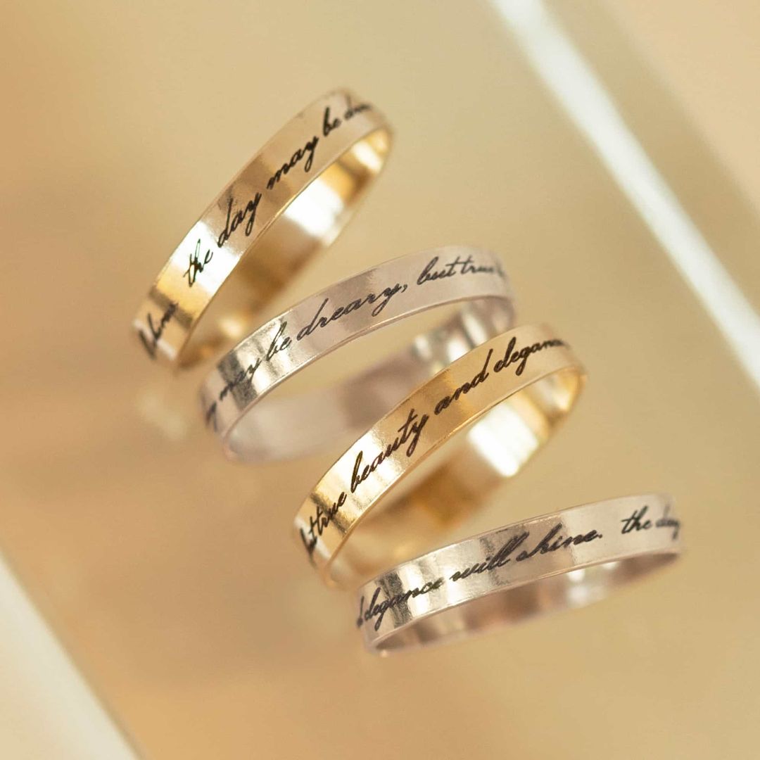 A personalized message ring in 18k gold-plated sterling silver, worn on a finger and engraved with the words 'Je t'aime'.