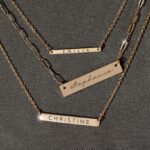 A personalized horizontal bar necklace in 18k gold-plated sterling silver, engraved with the name 'Amelia', on a delicate chain.
