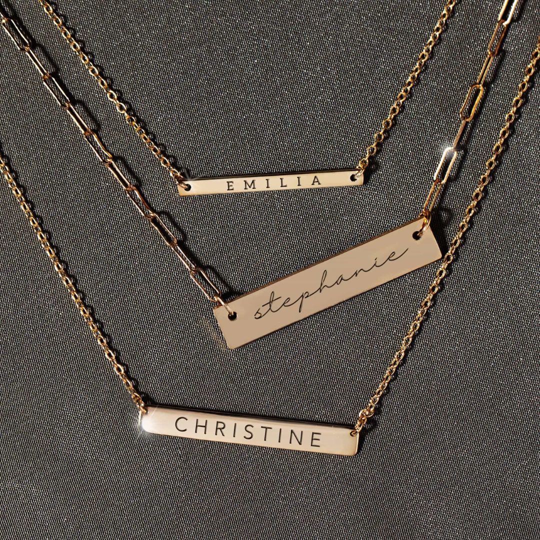 A personalized horizontal bar necklace in 18k gold-plated sterling silver, engraved with the name 'Amelia', on a delicate chain.
