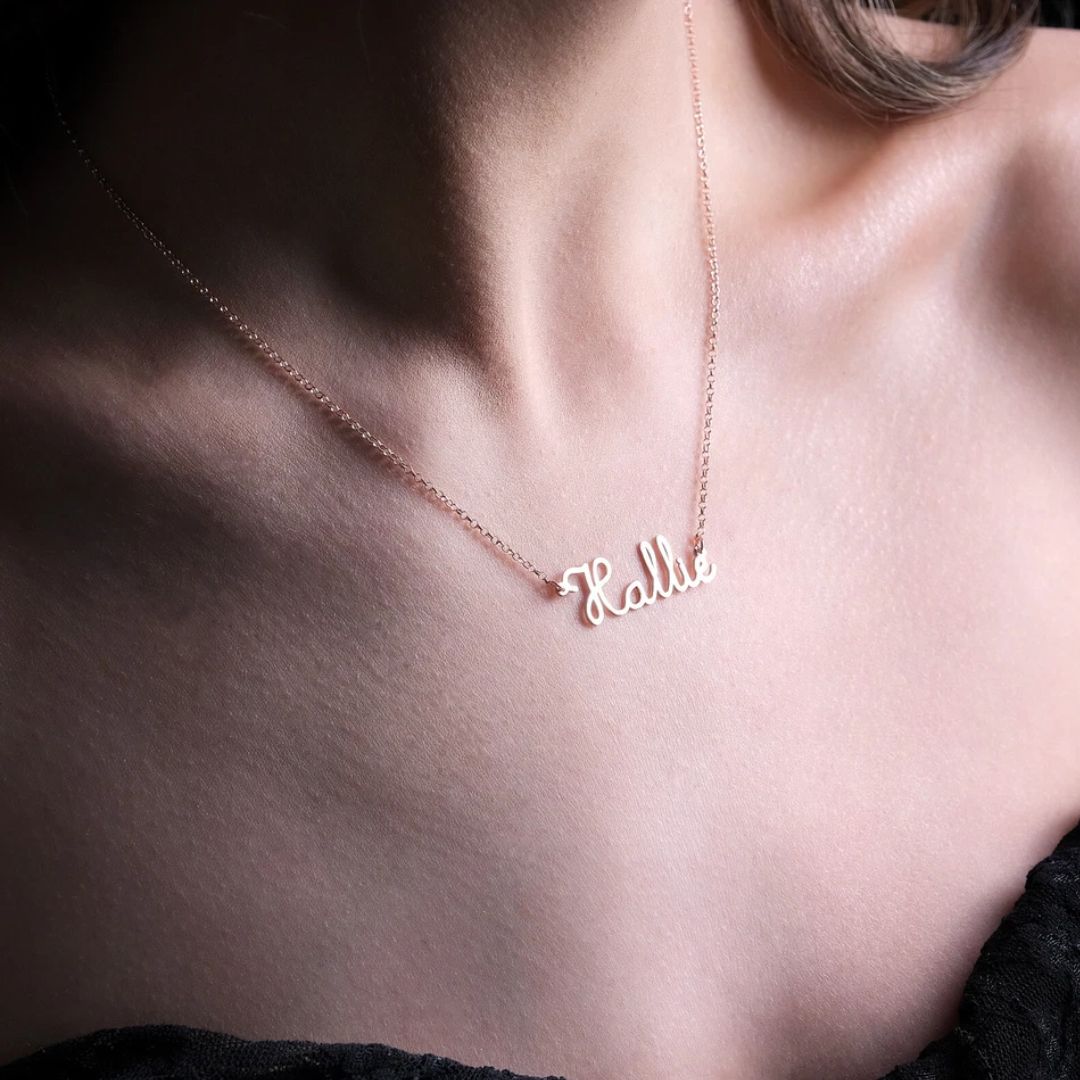 Personalized 'Olivia' name necklace in 18k rose gold-plated sterling silver, hanging from a delicate chain on a neutral background.