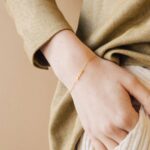 Whisper-thin 'Zoe' name bracelet in 18k gold-plated sterling silver, shown delicately on a woman's wrist.