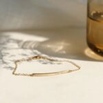 A minimalist personalized bar bracelet in 18k gold-plated sterling silver, engraved with the name 'Ava', worn delicately on a wrist.
