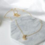 Luna Crescent Moon necklace in 18k gold-plated sterling silver, showing the polished pendant on a delicate chain.