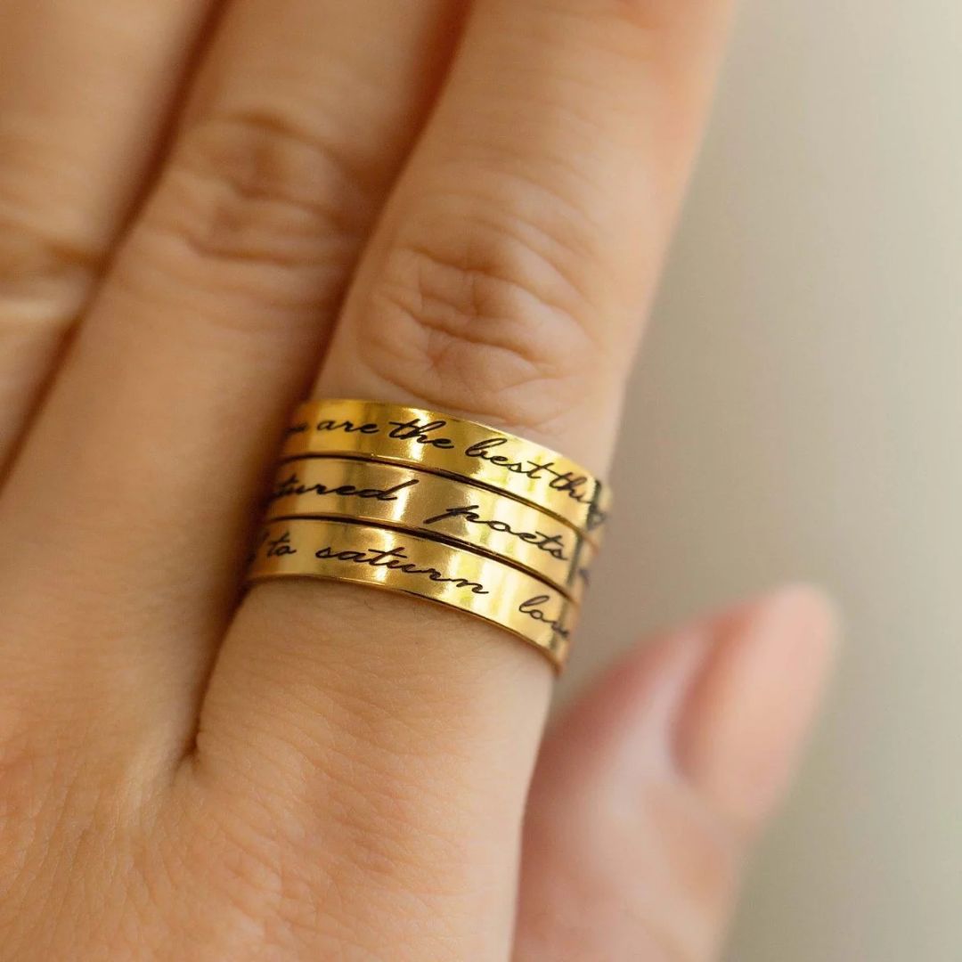 A personalized message ring in 18k gold-plated sterling silver, worn on a finger and engraved with the words 'Je t'aime'.