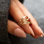 A dainty personalized signet ring in 18k gold-plated sterling silver, engraved with the initial 'S' and worn on a finger.