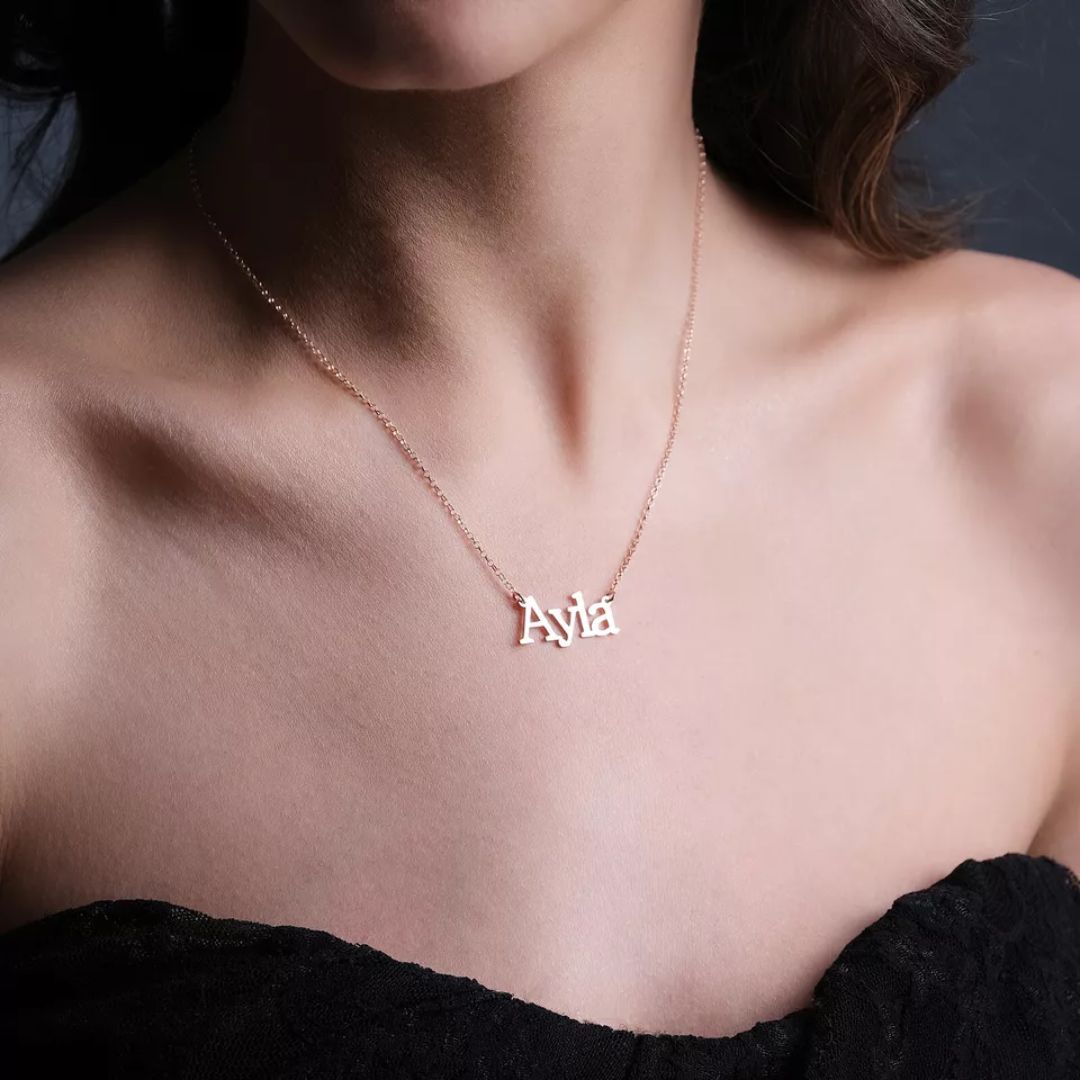 Personalized 'Olivia' name necklace in 18k rose gold-plated sterling silver, hanging from a delicate chain on a neutral background.
