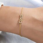 Dainty 'Madison' name bracelet in 18k gold-plated sterling silver, fully 'iced out' with sparkling crystals, on a woman's wrist.