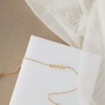 Whisper-thin 'Zoe' name bracelet in 18k gold-plated sterling silver, shown delicately on a woman's wrist.