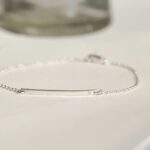 A minimalist personalized bar bracelet in 18k gold-plated sterling silver, engraved with the name 'Ava', worn delicately on a wrist.