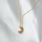 Luna Crescent Moon necklace in 18k gold-plated sterling silver, showing the polished pendant on a delicate chain.