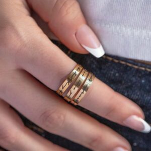 A personalized message ring in 18k gold-plated sterling silver, worn on a finger and engraved with the words 'Je t'aime'.