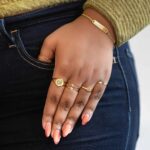 A dainty personalized signet ring in 18k gold-plated sterling silver, engraved with the initial 'S' and worn on a finger.