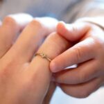 A dainty personalized heart initial 'A' ring in 18k gold-plated sterling silver, worn on a woman's finger.