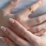 A personalized message ring in 18k gold-plated sterling silver, worn on a finger and engraved with the words 'Je t'aime'.