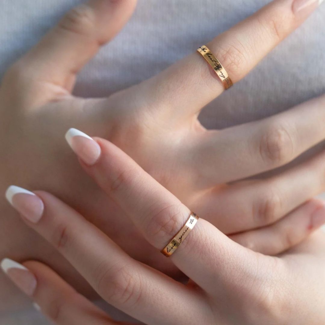 A personalized message ring in 18k gold-plated sterling silver, worn on a finger and engraved with the words 'Je t'aime'.