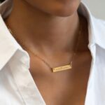 A personalized horizontal bar necklace in 18k gold-plated sterling silver, engraved with the name 'Amelia', on a delicate chain.