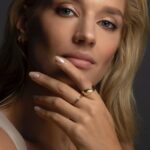 A dainty personalized heart initial 'A' ring in 18k gold-plated sterling silver, worn on a woman's finger.