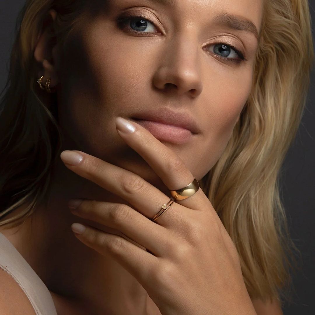 A dainty personalized heart initial 'A' ring in 18k gold-plated sterling silver, worn on a woman's finger.