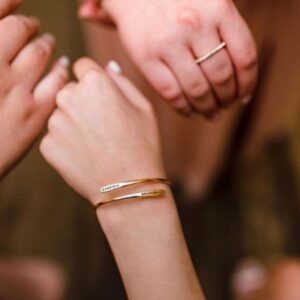 A signature custom engraved bangle in 18k gold-plated sterling silver, worn on a woman's wrist and engraved with the name 'Eleanor'.