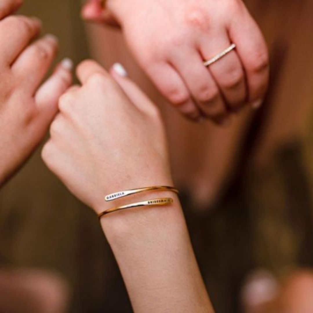 A signature custom engraved bangle in 18k gold-plated sterling silver, worn on a woman's wrist and engraved with the name 'Eleanor'.