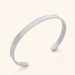 A wide Ayatul Kursi cuff bracelet in 18k rose gold-plated sterling silver, showing the intricate Arabic engraving of The Throne Verse on a woman's wrist.