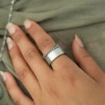 A woman's hand wearing the Cuban Link Chain Ring in 18k gold-plated sterling silver, showing the interlocking links wrapped around the finger.