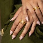 A woman's hand wearing the Cuban Link Chain Ring in 18k gold-plated sterling silver, showing the interlocking links wrapped around the finger.