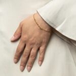 A Dainty Mama Script Bracelet in 18k gold-plated sterling silver, worn on a woman's wrist.