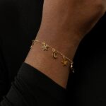 A delicate Celestial Moon and Star link bracelet in 18k gold-plated sterling silver, worn on a woman's wrist.