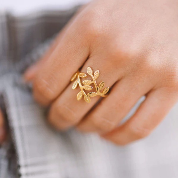 A delicate Olive Branch Peace Ring in 18k gold-plated sterling silver, worn on a finger to showcase the leaf design wrapping around it.
